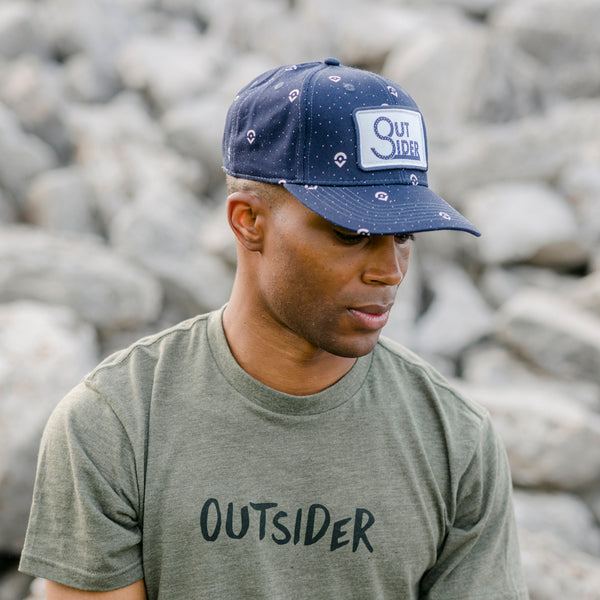 Outsider Blue Adjustable Snapback Hat with white dots and white patch modeled on a man