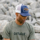 Outsider Authentic Goods Blue, White, and Yellow Adjustable Snapback Hat modeled on a man